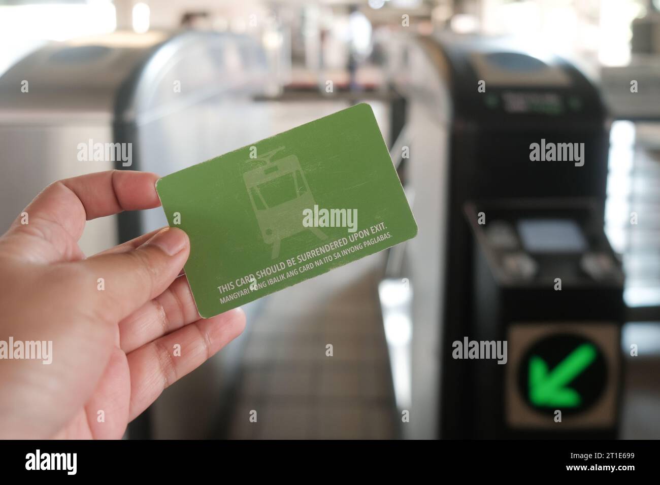 Manila, Philippines: hand holds Light Rail Transit 1 Single Journey Ticket in front of tap machines. Close-up of single-use LRT Line 1 ticket. Stock Photo