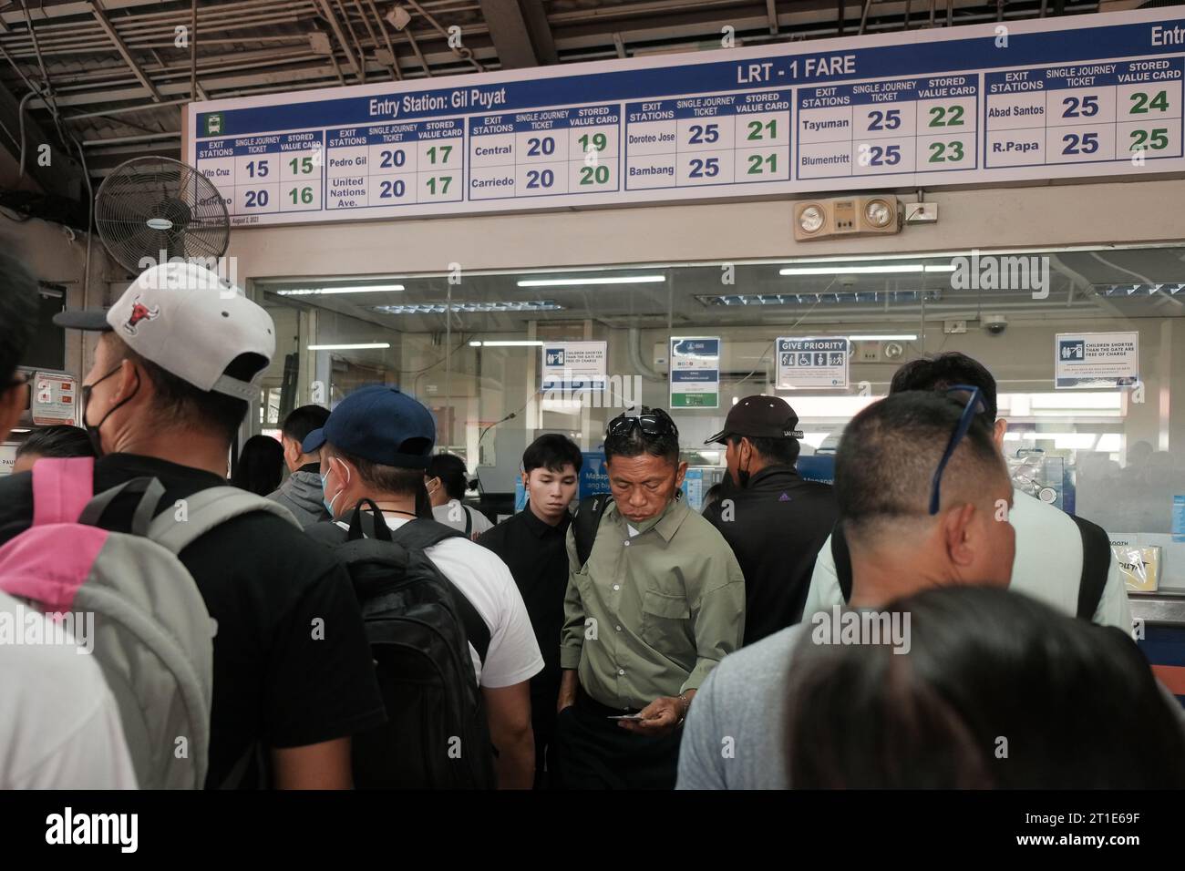 Manila, Philippines: commuters line up inside Gil Puyat Train Station to buy single journey tickets from Light Rail Transit 1 ticket booth. Busy metro. Stock Photo