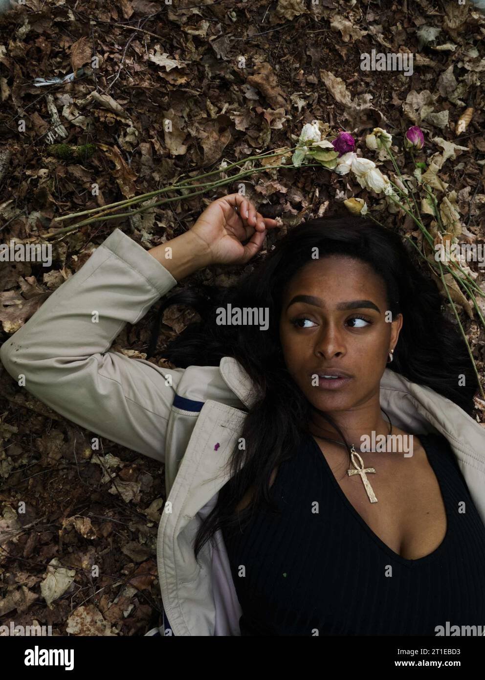 young black woman wearing gold ankh laying in the dead leaves of a forest floor Stock Photo Alamy