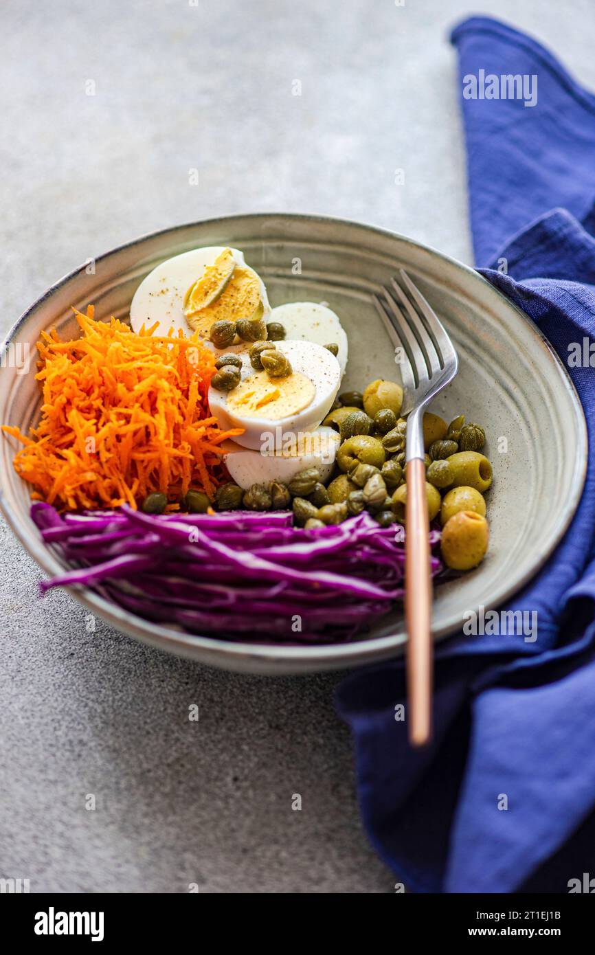 Bowl with boiled eggs, capers, olives, red cabbage, and carrots (Keto cuisine) Stock Photo