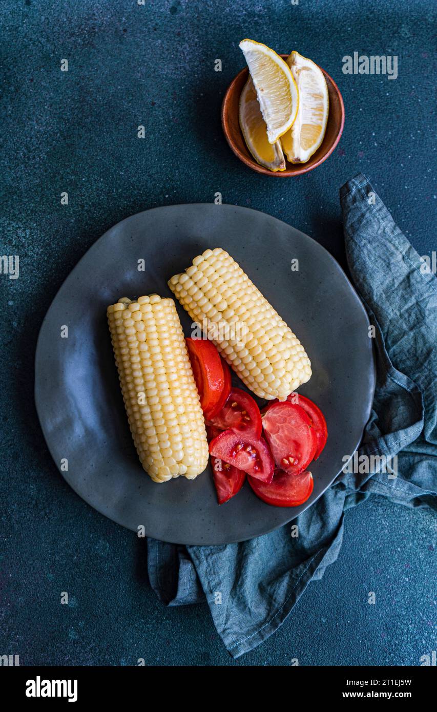 Cooked white corn on the cob with tomatoes Stock Photo