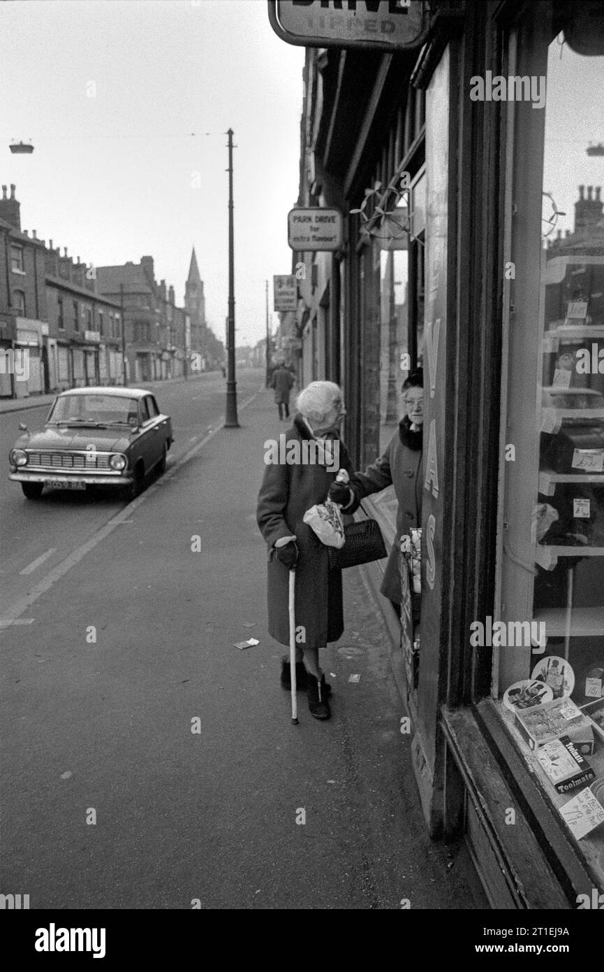 Two elderly ladies stood talking in a tobacconist newsagents shop doorway during the slum clearance and demolition of St Ann's, Nottingham. 1969-1972. Stock Photo