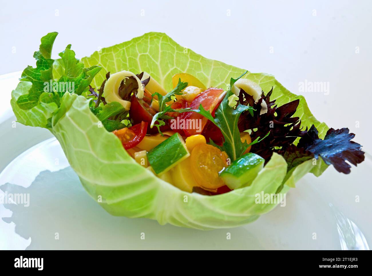 White cabbage leaf bowl with mixed vegetable salad and herbs Stock Photo