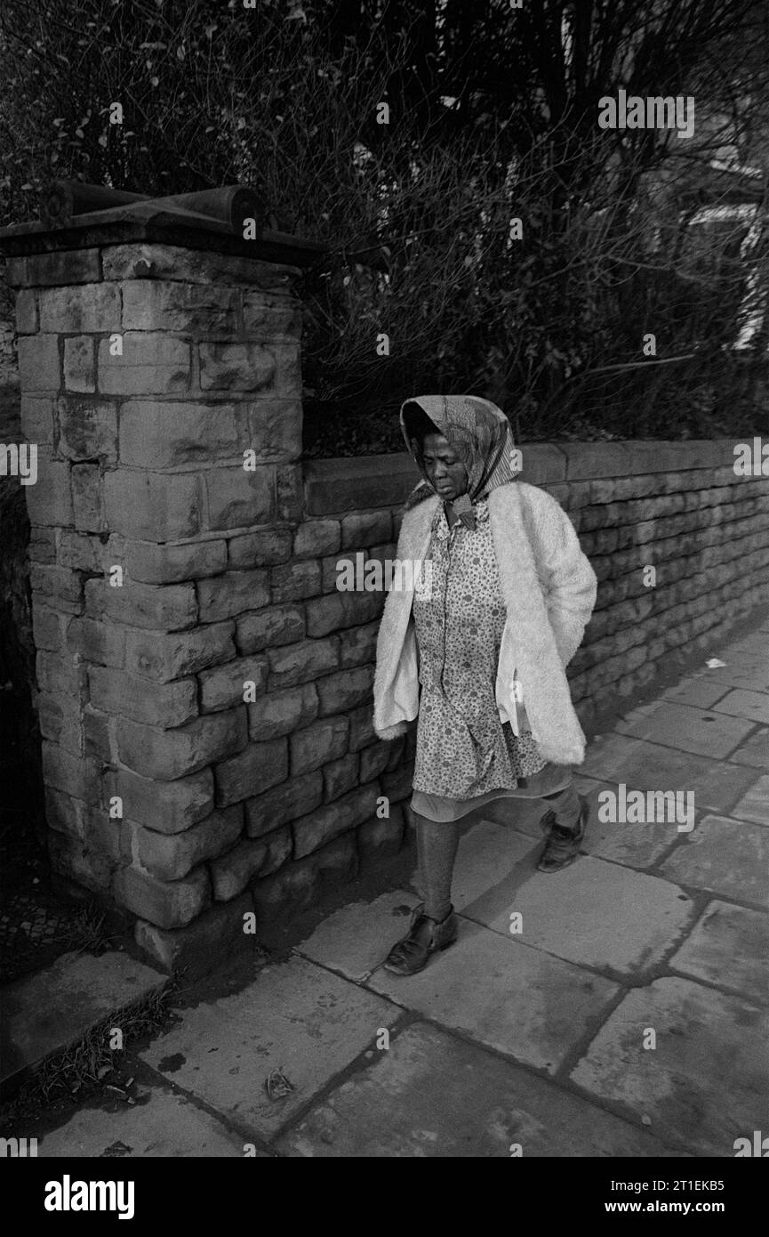 Black lady, wearing a headscarf and smock, walking along Woodborough Road during the slum clearance and demolition of St Ann's, Nottingham. 1969-1972 Stock Photo