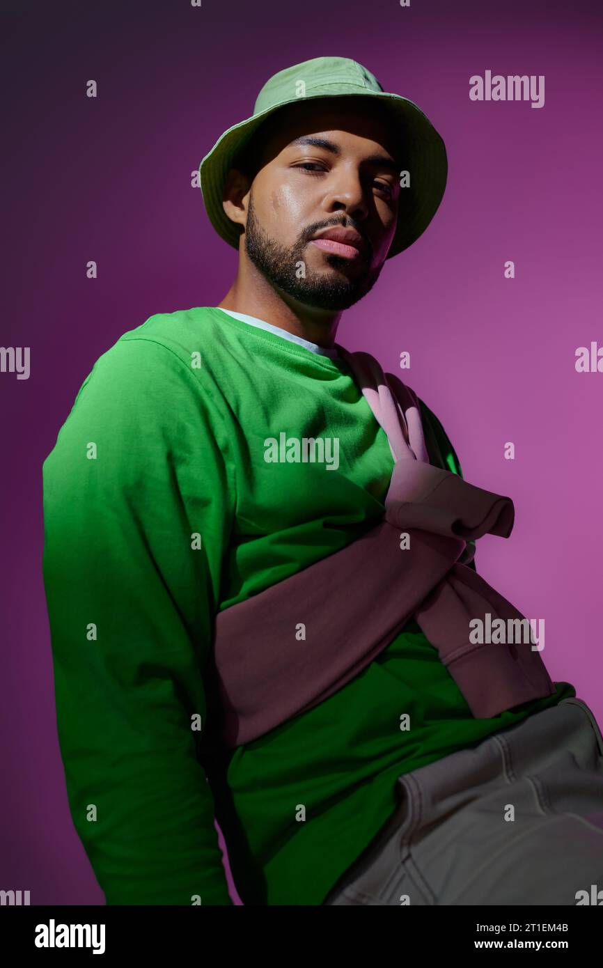 young handsome man in green panama with purple sweatshirt tied on his shoulders, fashion concept Stock Photo