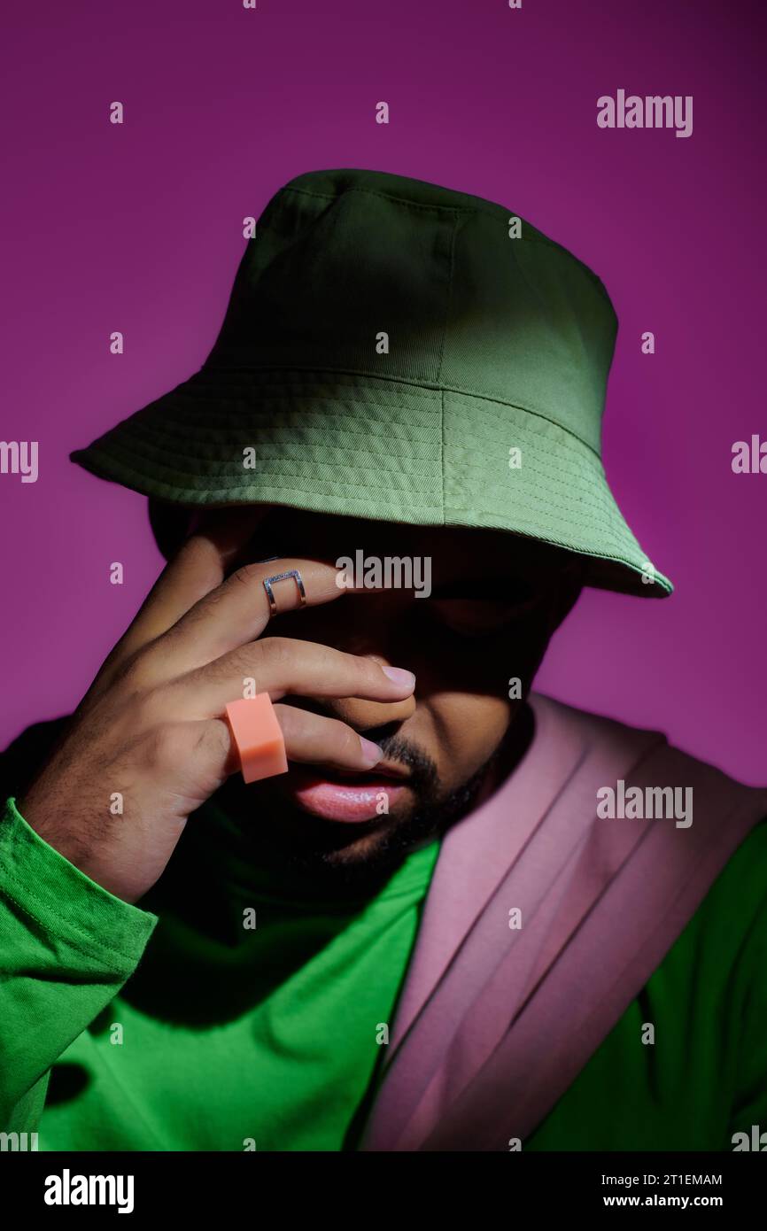 close up of good looking man with rings on fingers in panama closing face with hand, fashion