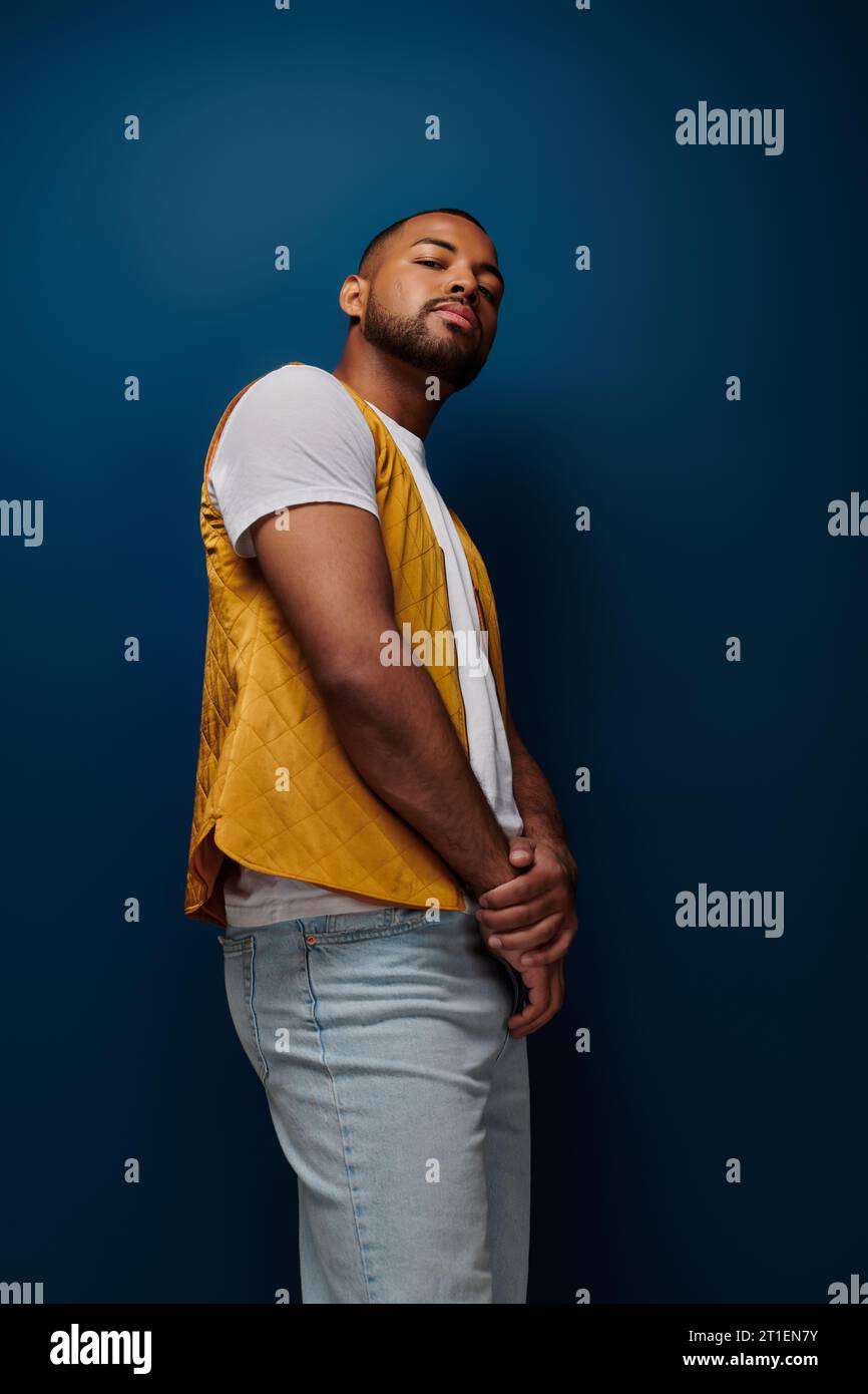 stylish african american man in yellow vest posing in profile and ...