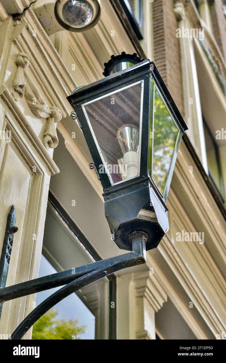a street light hanging on the side of a building with trees in the