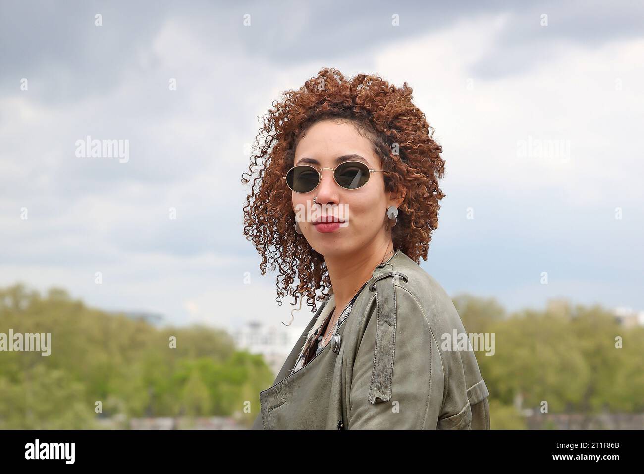 Head portrait of a cute curly hair woman with dark sunglasses smiling Stock Photo