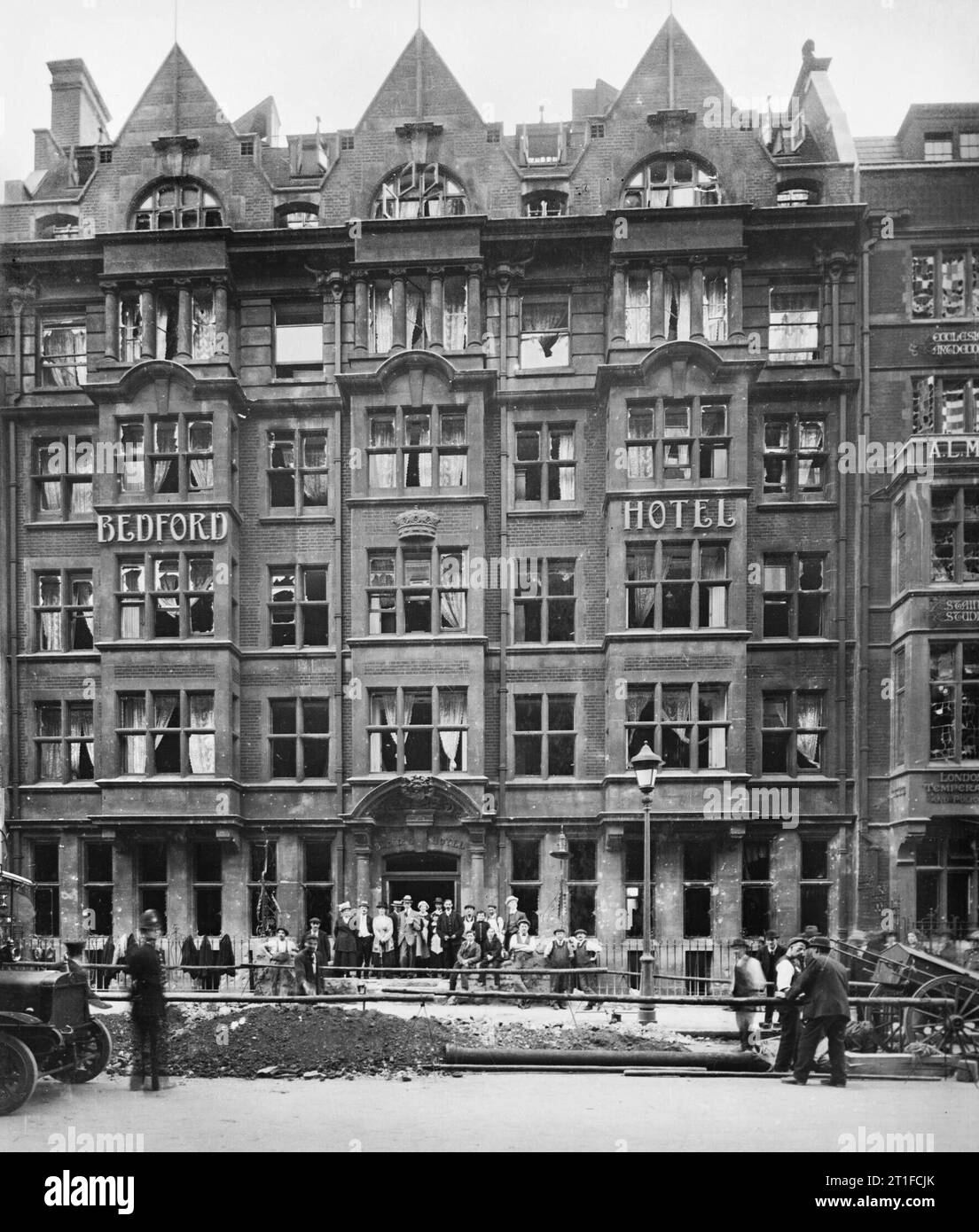 Air Raid Damage in the United Kingdom during the First World War. A group of people stand outside the Bedford Hotel on Southampton Row to watch at men at work beside a large crater. The damage was caused by a 50 kilogram bomb during a Gotha raid on the night of 24 - 25 September 1917. Stock Photo