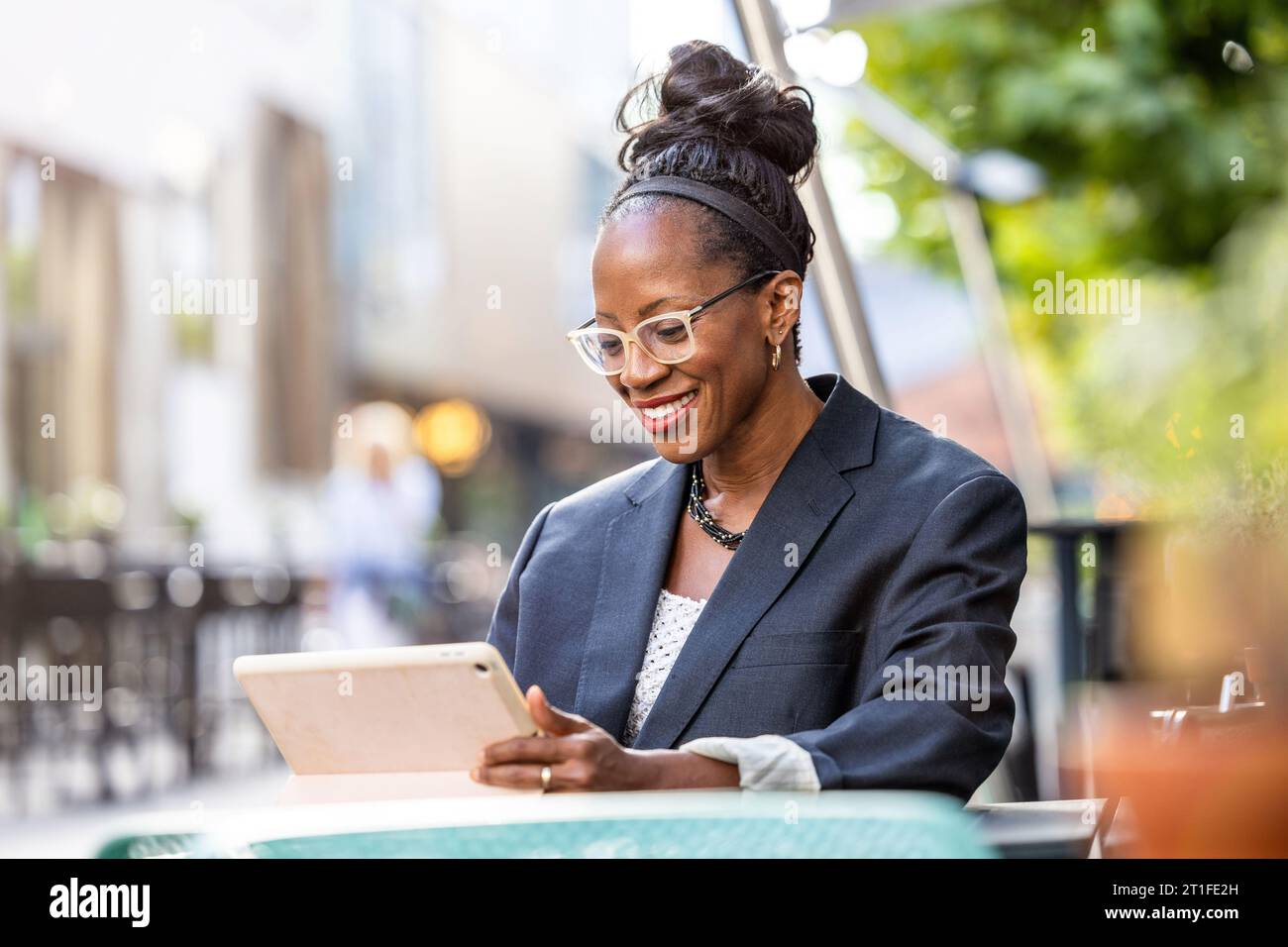 Portrait of happy businesswoman using tablet computer in outdoor cafe Stock Photo