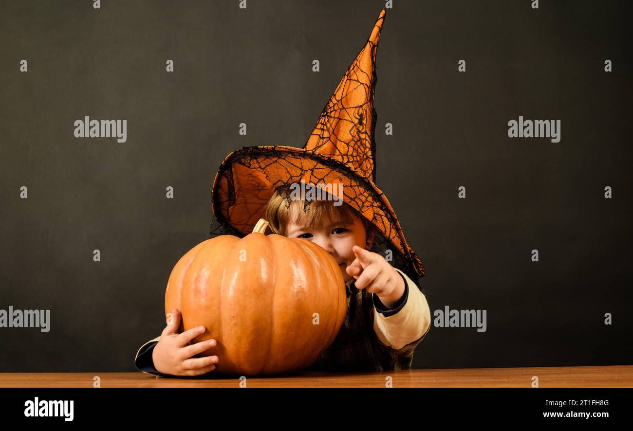 Happy Halloween. Little kid wizard with Jack-o-lantern preparing for Halloween holidays. Smiling child boy in witch hat with Halloween pumpkin Stock Photo