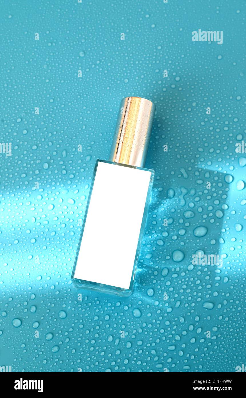 Perfume bottle with mock up on blue background with hard light and water drops. with shadows flat lay, top view Stock Photo