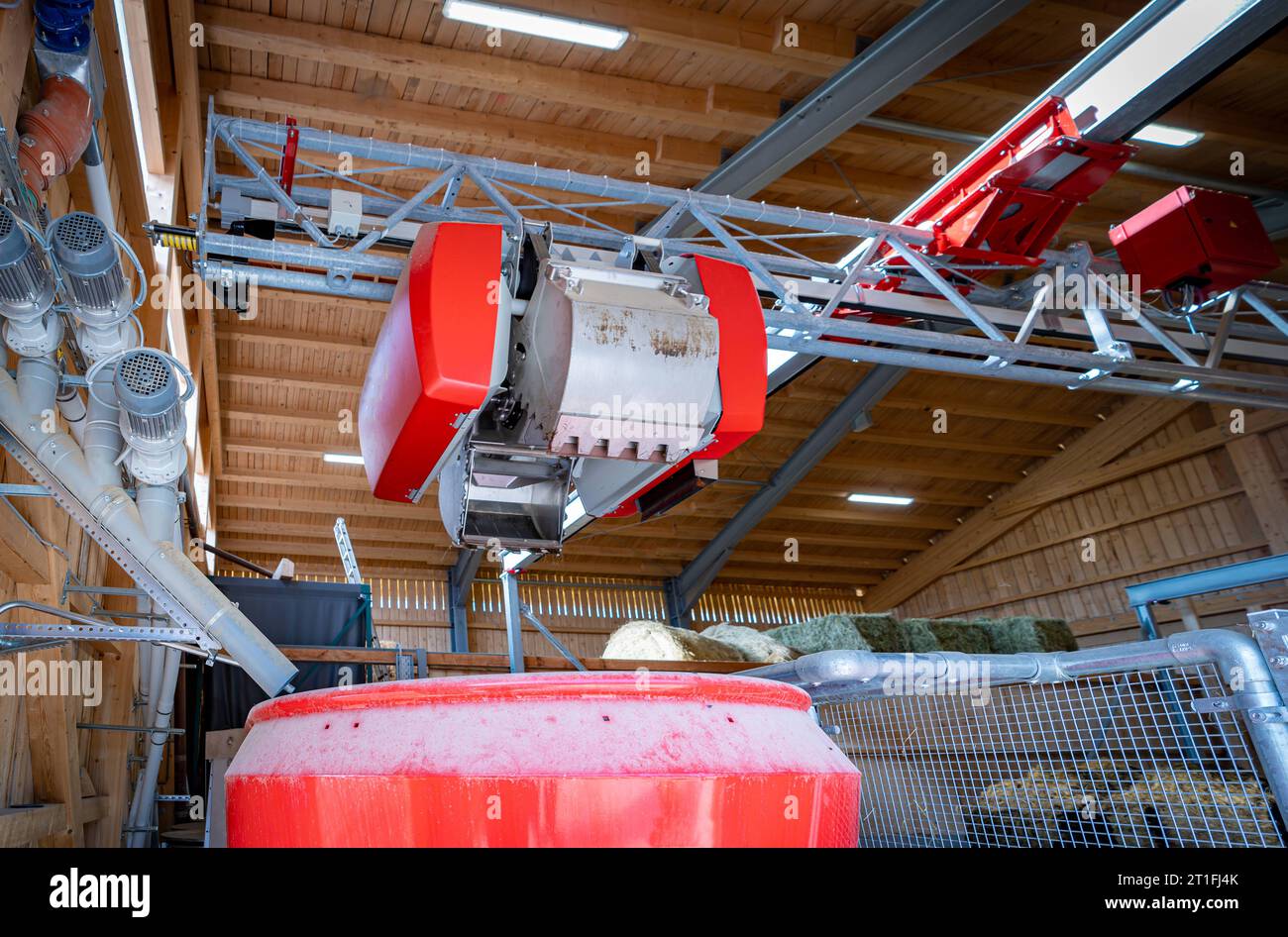 Moderner Fütterungsroboter im Futterlager, Befüllung des Mischbehälters mit Futterkomponenten mittels eines kleinen Krans. Moderner Fütterungsroboter der Firma Lely sucht sich die Futterkomponenten in einem eigens dafür vorgesehenen Futterlager selbtsständig zusammen. Über Laserabtastung kann ein separater Greifarm die Position z.B. von vorher dort bereitgestellten Silageblöcken erkennen und den mobilen Futterroboter befüllen. Die Komponenten werden im Voratsbehälter des Roboters gemischt und entlang einer Bahn im Kuhstall den Kühen vorgegeben. Süddeutschland Bayern Deutschland *** Modern feed Stock Photo