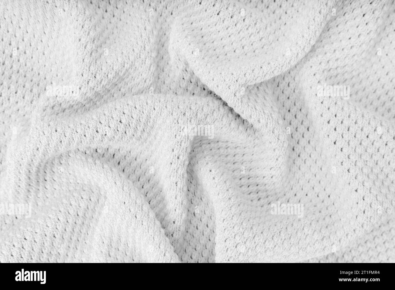 White color crumpled, wrinkled knitting wool cloth texture. Background of knitted fabric with dots pattern. Textile structure, cloth surface, weaving Stock Photo