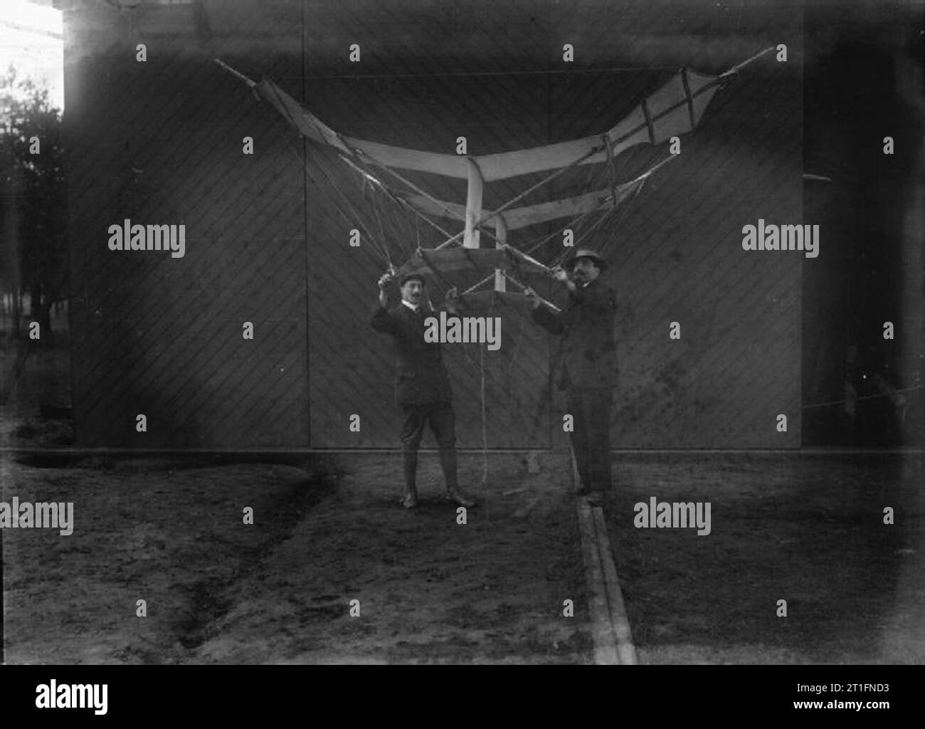 Aviation in Britain Before the First World War A very clear photograph of Cody with Mr. Morton holding an extended wing kite with an unusual configuration next to the wooden wall of Cody's shed on Laffan's Plain. Cody used much larger versions of this type of kite in his man lifting kite system. According to Cody he was fascinated by kites from a young age, when he saw the Chinese cooks who worked on the cattle drives making and flying toy kites. Like many of Cody's tales of his early life, it is difficult to say whether this is true or not.. In friendly competition he and his sons used to bui Stock Photo