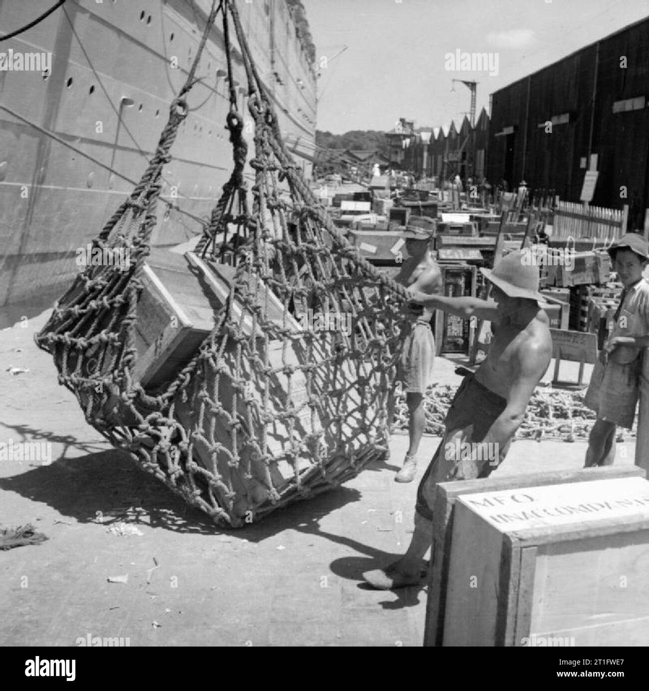 Demobilization of British Service Personnel At Singapore docks baggage belonging to British officers returning to the United Kingdom for demobilisation is loaded aboard the the liner MAURETANIA using cargo nets. Stock Photo