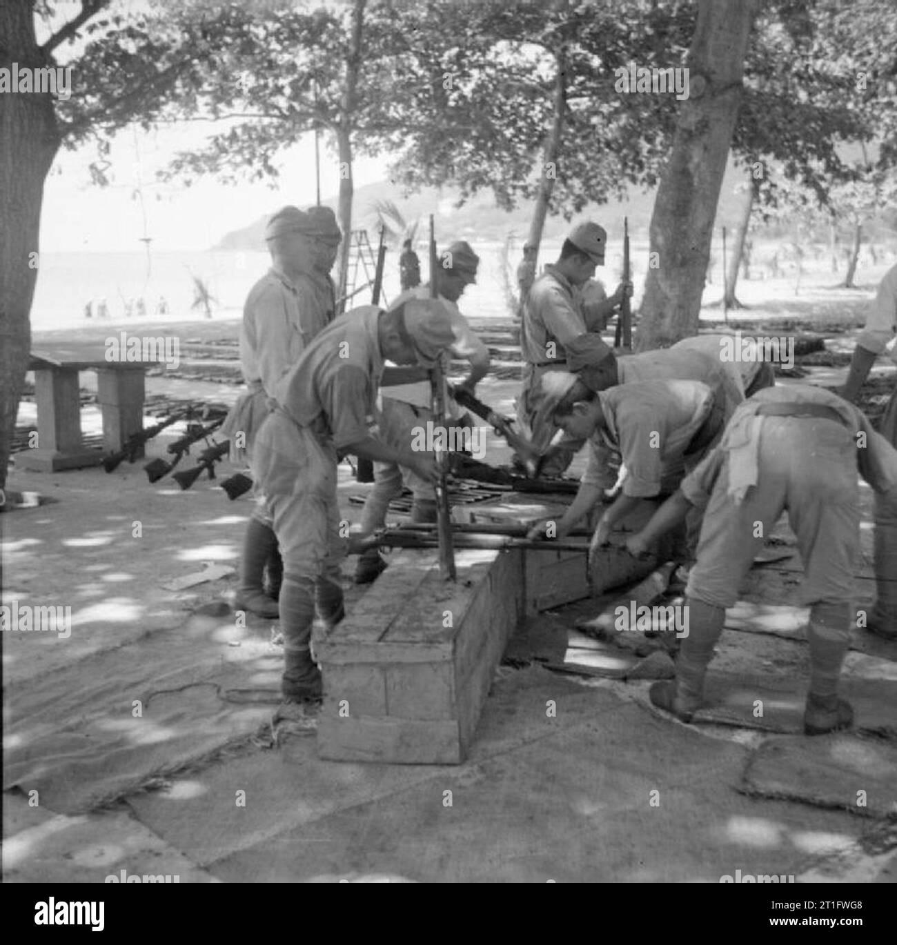 The Allied Reoccupation of French Indo-china Japanese prisoners of war clean and oil some of the thousands of surrendered weapons at the prisoner of war camp at Cape Saint Jacques. Stock Photo