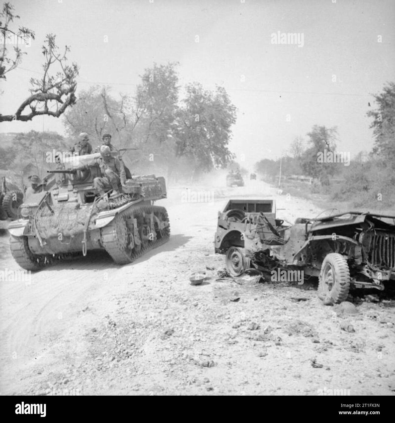 The British Army in Burma 1945 A Stuart tank, crewed by members of the 19th Indian Division, passes a destroyed jeep on the outskirts of Mandalay shortly after the fall of Fort Dufferin, 19 March 1945. Stock Photo