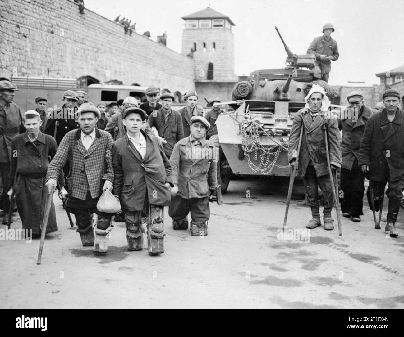 Crippled Russian and Polish prisoners stand in front of a US armoured vehicle belonging to the US 11th Armoured Divison. This image was taken at Mauthausen concentration camp. Stock Photo