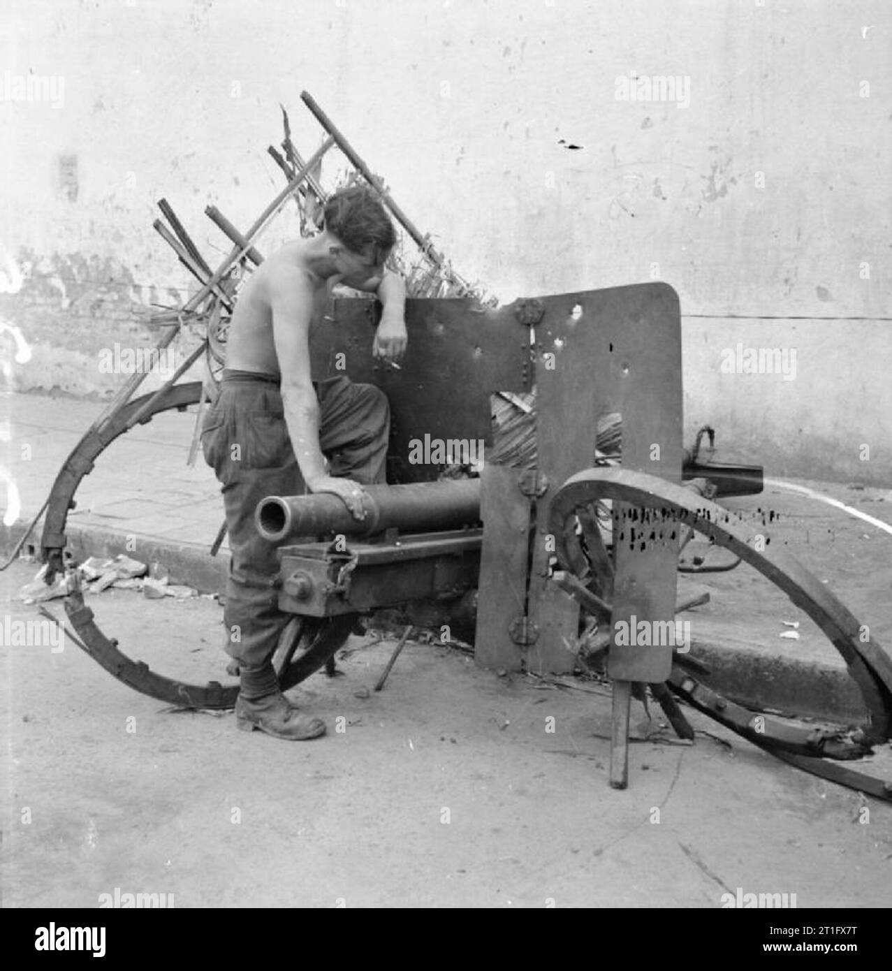 The British Occupation of Java A man of the 1st Battalion, The West Yorkshire Regiment examines a Japanese artillery piece that was used by Indonesian nationalists during the fighting in Surabaya (Soerabaja) until destroyed by British forces. Stock Photo