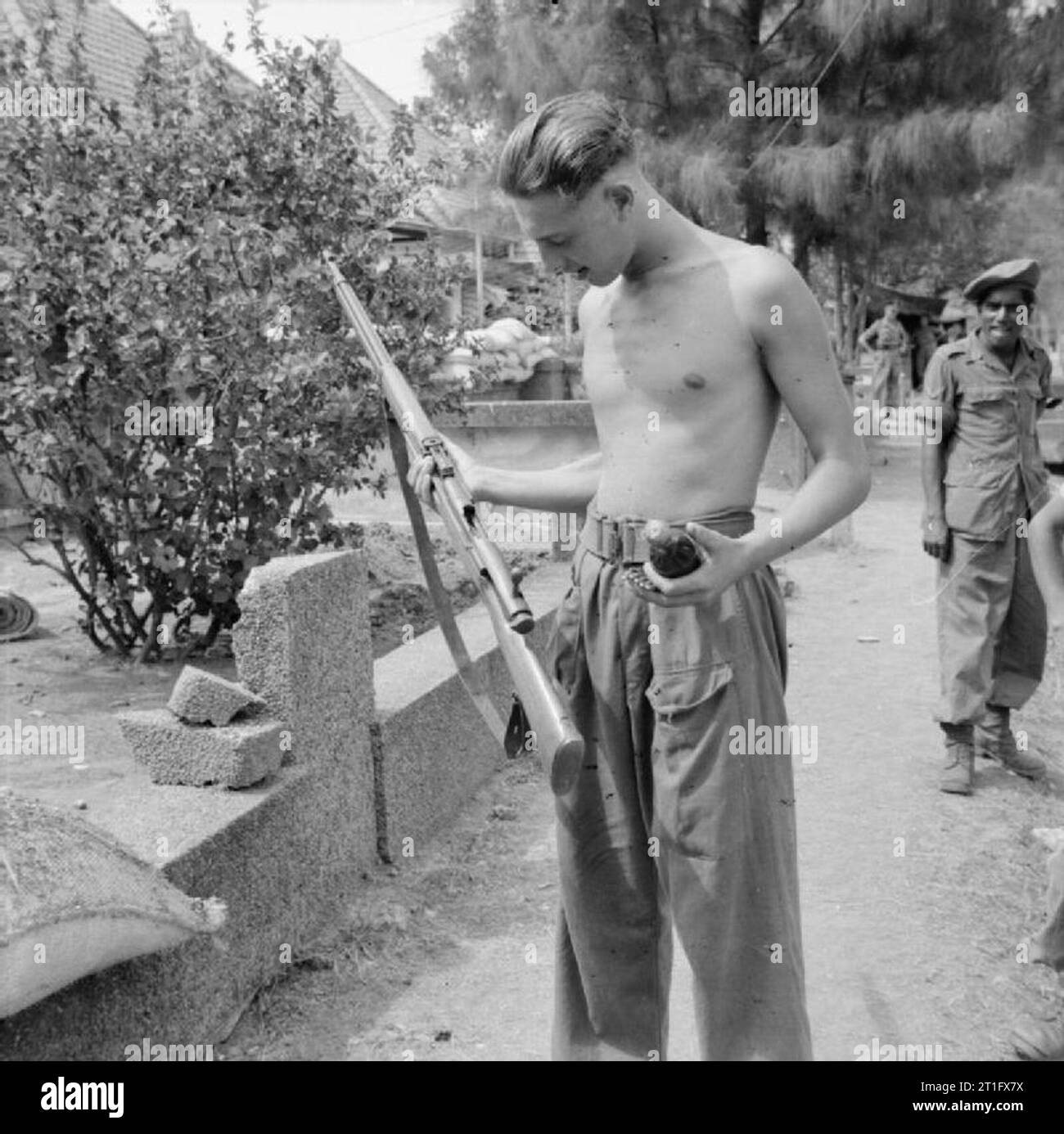 The British Occupation of Java A British soldier holding a Japanese rifle and a molotov cocktail, typical weapons used by Indonesian nationalists in the fighting in Surabaya (Soerabaja). Stock Photo