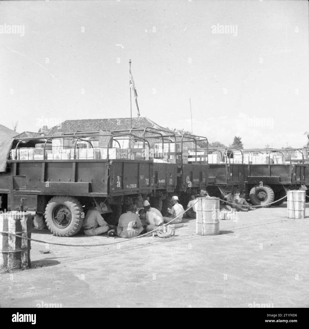 The British Occupation of Java Japanese prisoners of war sit in the shade of lorries they have just loaded with some of the 100 tons of supplies flown daily into the city of Bandoeng by Dakota aircraft of 31 Squadron, Royal Air Force. Due to ambushes and sabotage by Indonesian nationalists on the roads between Batavia and Bandoeng, the only secure supply route to the latter city was by air. Stock Photo