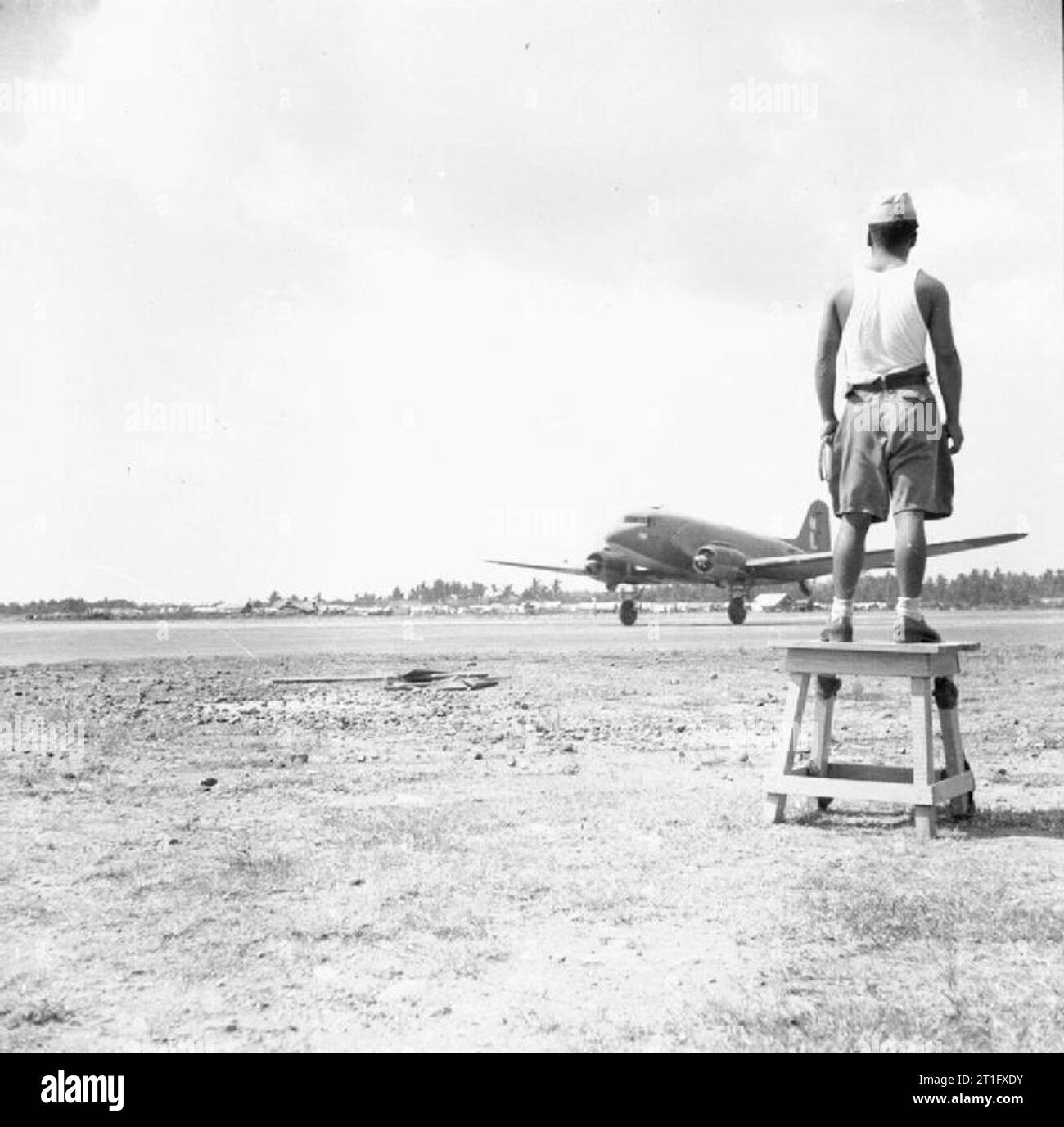 The British Occupation of Java A Japanese prisoner of war watches a Dakota aircraft of 31 Squadron, Royal Air Force land on the airstrip at Bandoeng. Due to ambushes and sabotage by Indonesian nationalists on the roads between Batavia and Bandoeng, the only secure supply route to the latter city was by air. Stock Photo