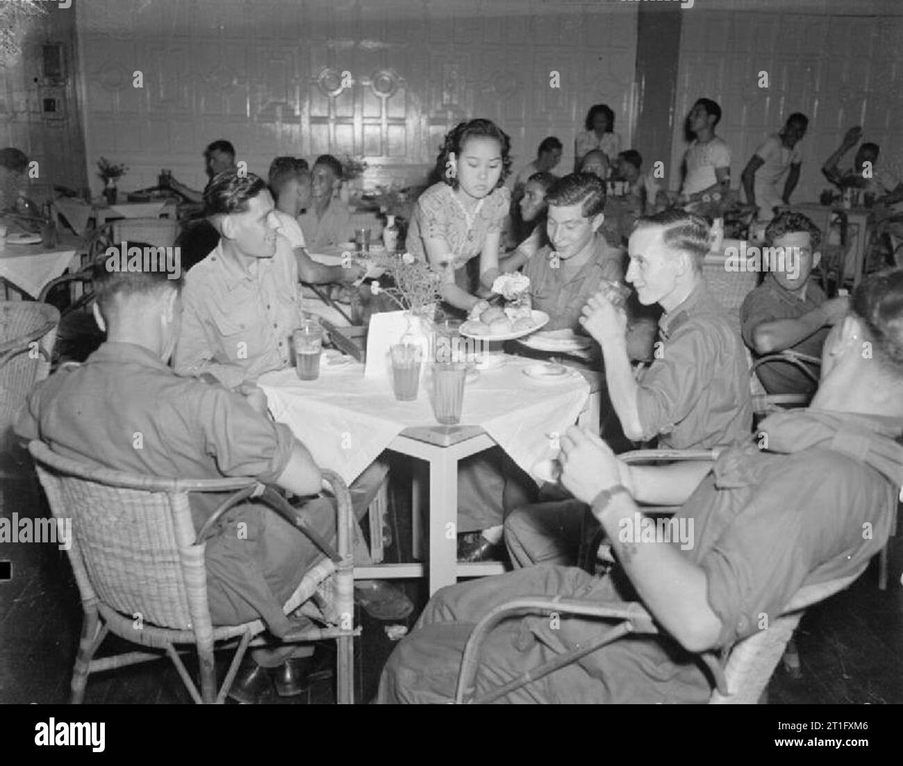The British Reoccupation of Singapore A Chinese waitress serves British troops in the newly opened NAAFI canteen in Raffles Place, Singapore. The canteen was known as the 'Shackle Club.' Stock Photo