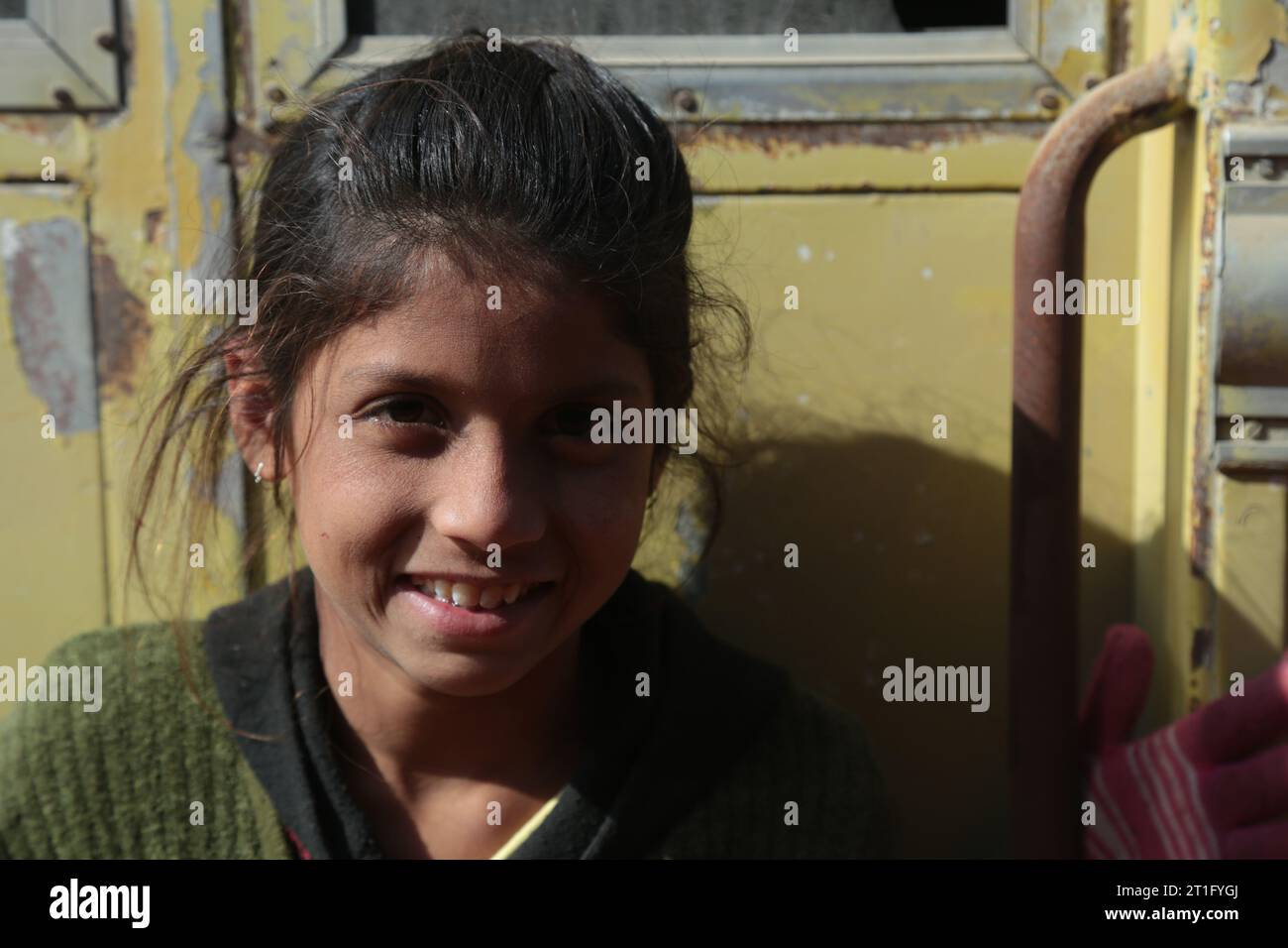 Beer Chhapar Rural, Rajasthan, India - January 18, 2017: Young Indian girl outside the yellow train door. Portrait Stock Photo