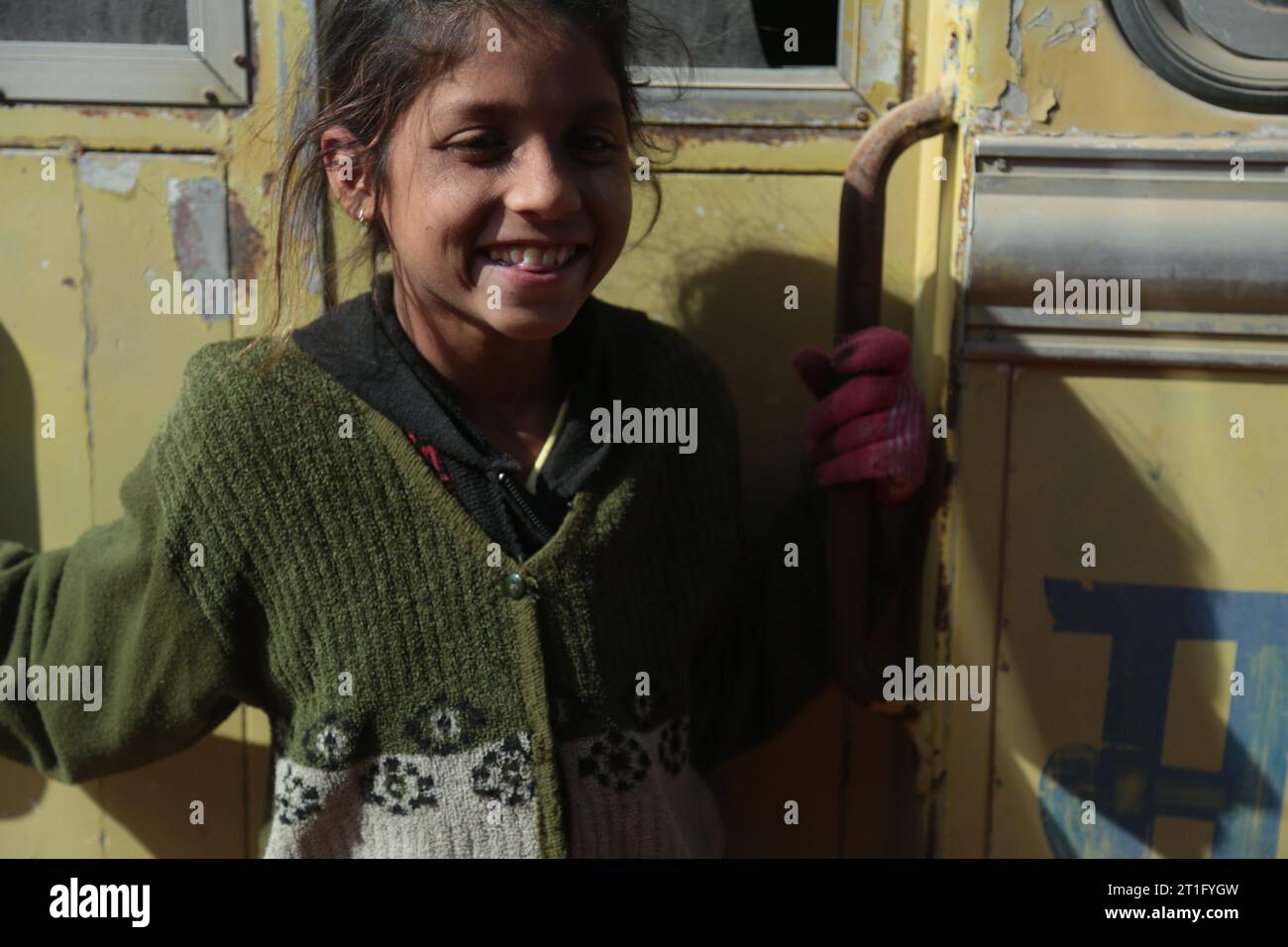 Beer Chhapar Rural, Rajasthan, India - January 18, 2017: Young Indian girl outside the yellow train door. Portrait Stock Photo
