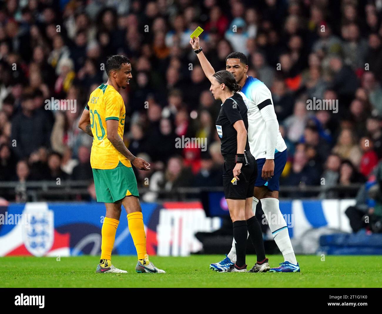 Referee Stephanie Frappart (centre) shows a yellow card to Australia's Keanu Baccus during the international friendly match at Wembley Stadium, London. Frappert is the first woman to officiate a men's international game at Wembley. Picture date: Friday October 13, 2023. Stock Photo