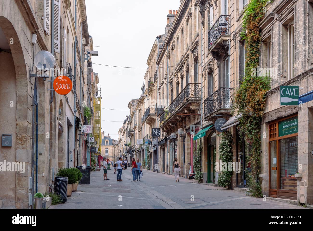 A pedestrianized shopping street in the city of Bordeaux in south-west France. Plants climb the exterior of the stone buildings. Stock Photo
