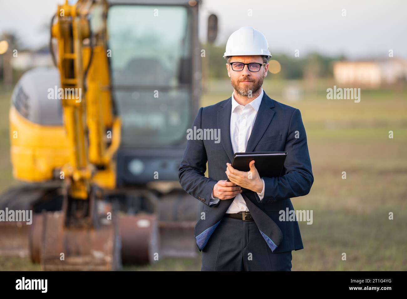 Civil engineer worker at a construction site. Engineer man in front of house background. Confident engineer worker at modern home building constructio Stock Photo