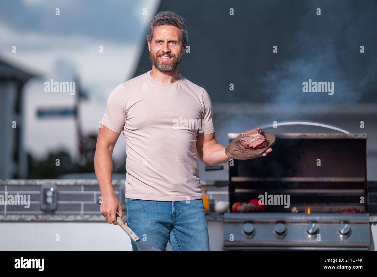 Grill cook. Chef with BBQ cooking tools. Barbecue and grill. Picnic and barbecue party. Chief cook with utensils for barbecue grill. Barbeque on holid Stock Photo