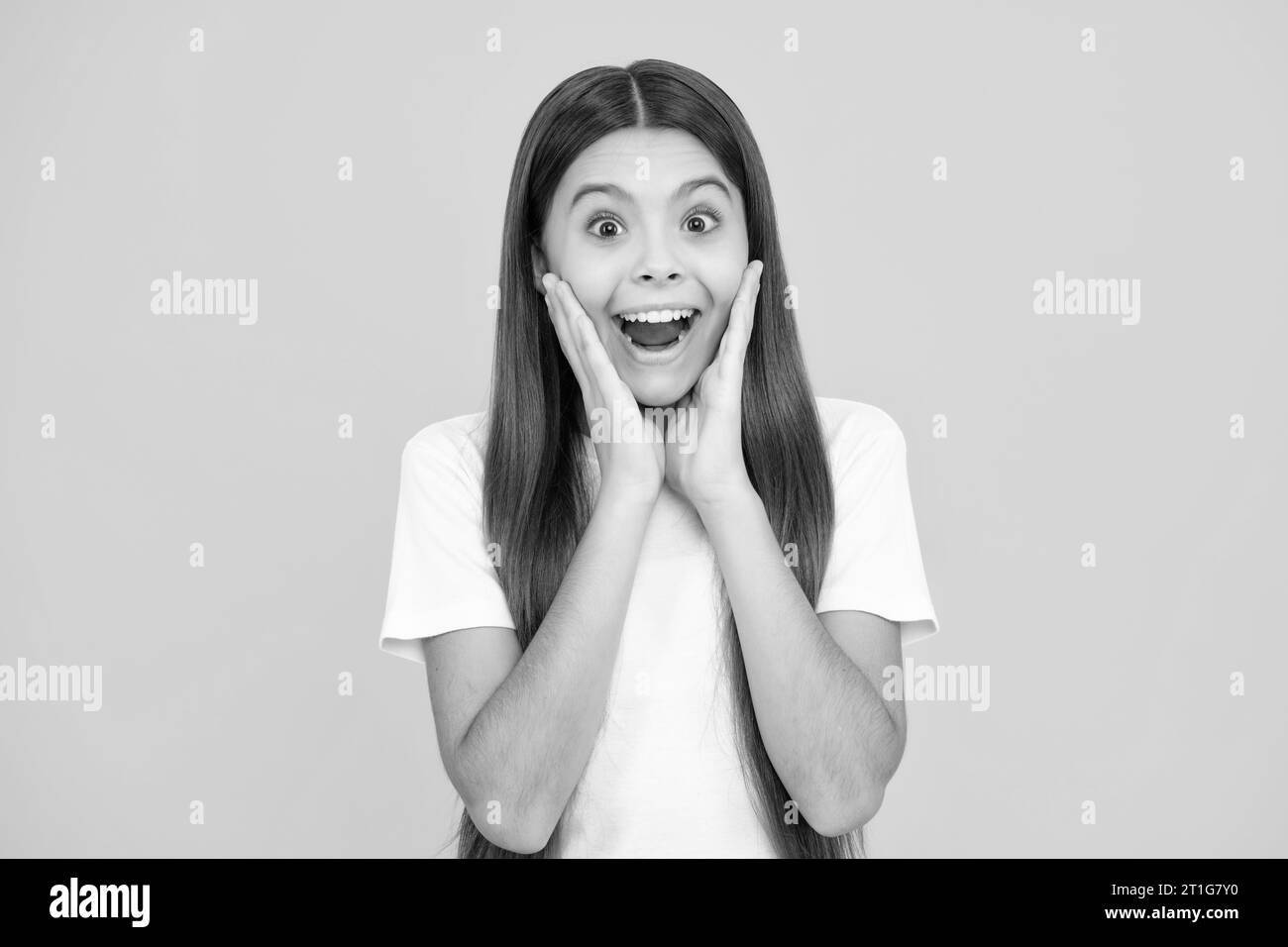 Teenager girl with shocked facial expression. Surprised face expression, isolated on yellow background. Excited teenager, glad amazed and overjoyed em Stock Photo