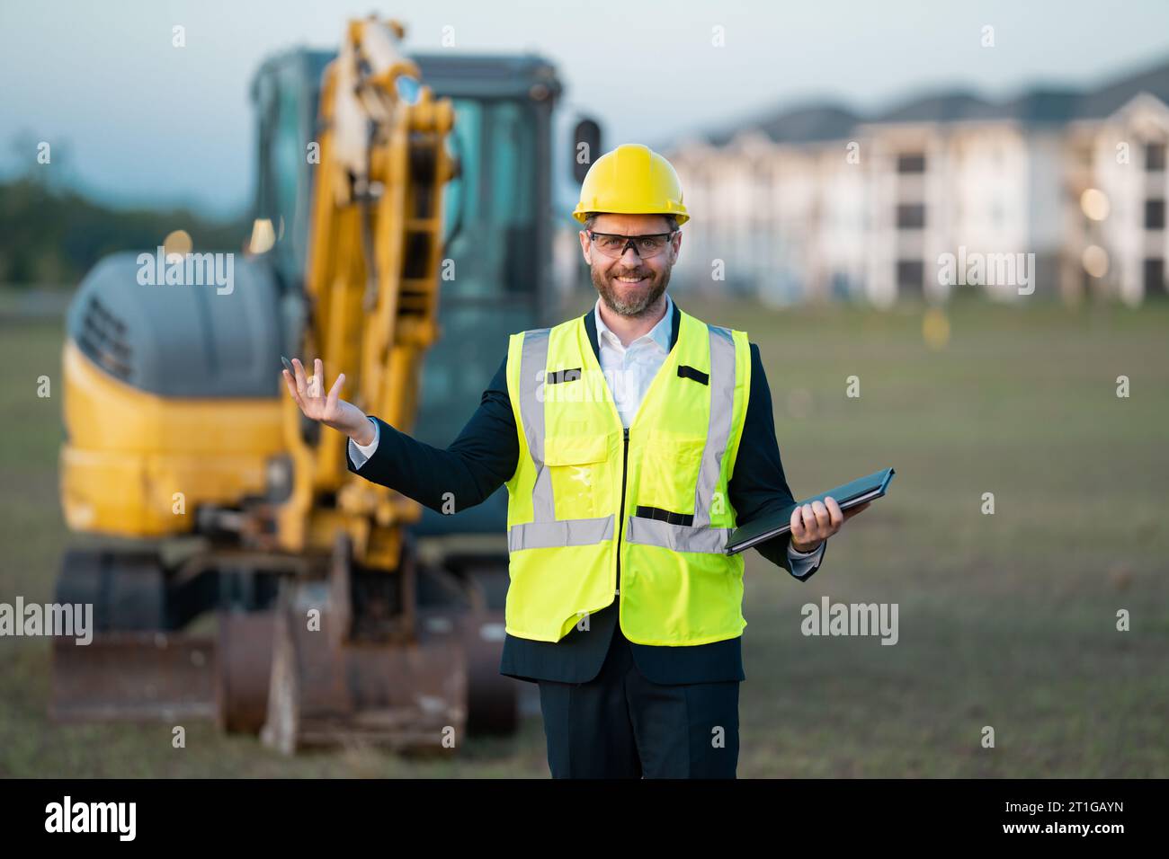 Civil engineer worker at a construction site. Engineer man in front of house background. Confident engineer worker at modern home building constructio Stock Photo