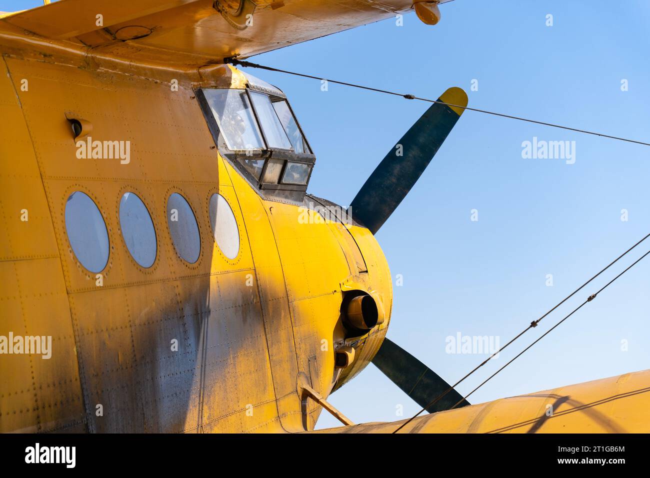 Cockpit of an old yellow-painted airplane with the blue sky in the background Stock Photo