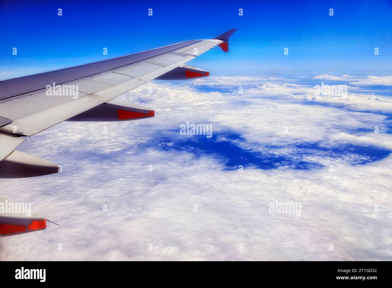 Passenger airplane wing with engines flying over Pacific ocean cloudscape to New Zealand. Stock Photo