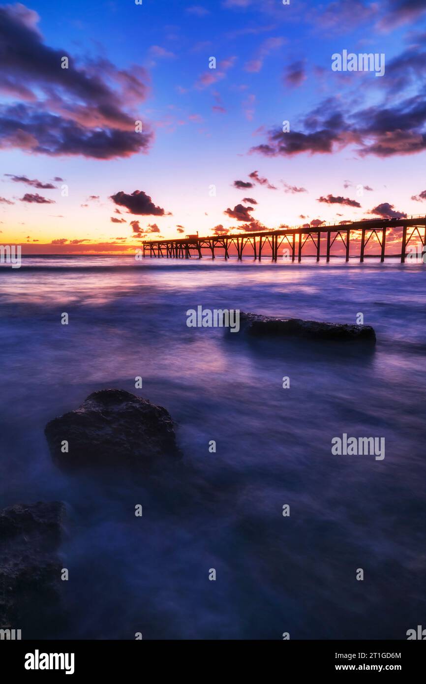 Colourful Pacific ocean seascape sunrise over Middle Camp beach historic jetty at Catherine Hill bay town in Australia. Stock Photo