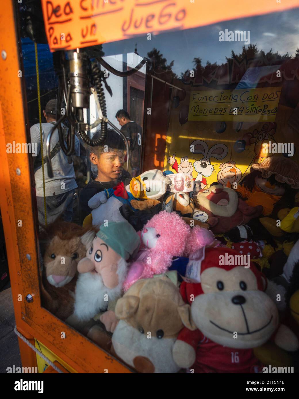 Boy looks yearningly at a 50 peso bill and stuffed animals to be won at the Jala, Nayarit fair in Mexico. Stock Photo