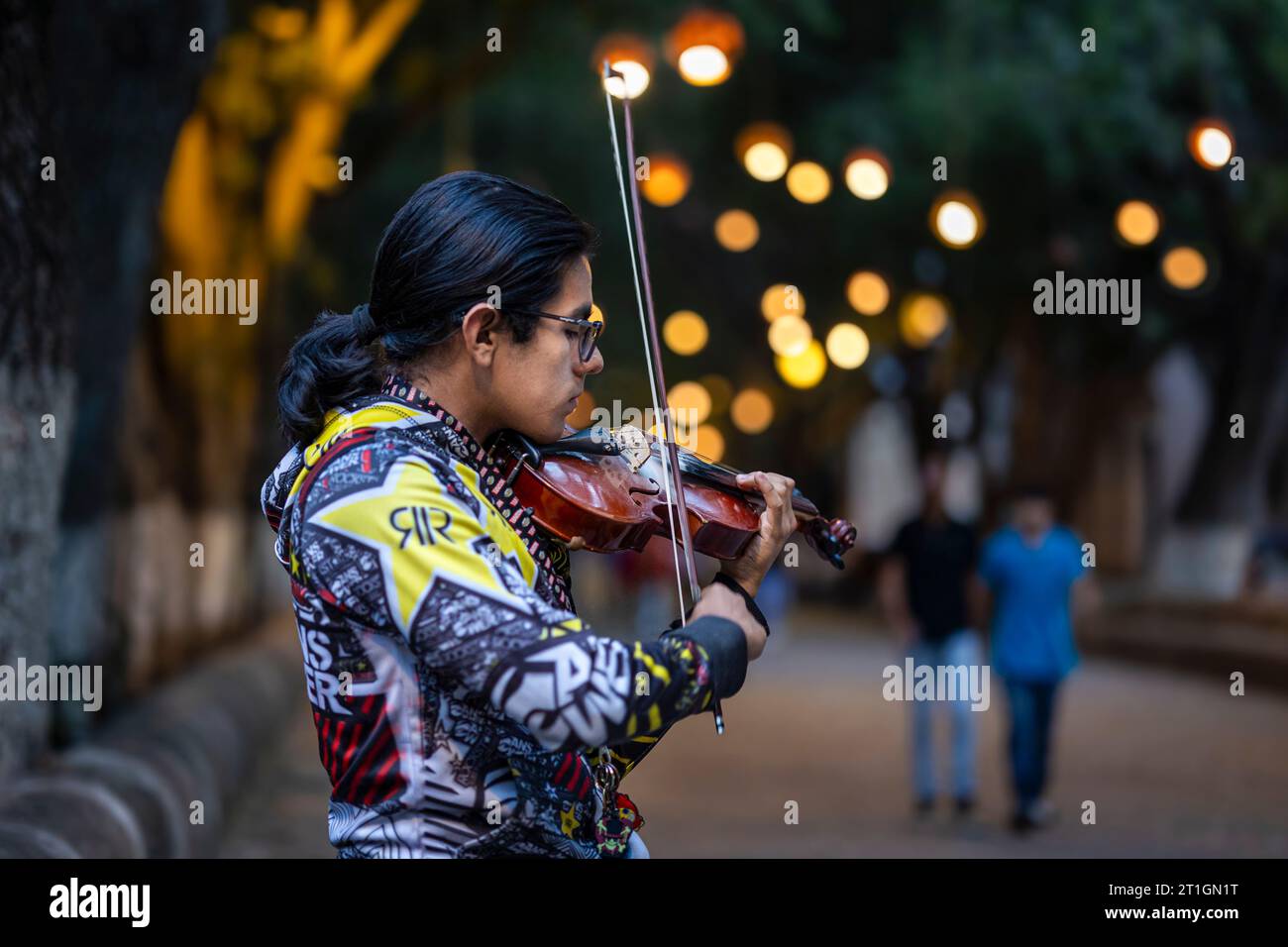 Young violinist makes a little extra income while practicing on the San Diego pedestrian mall in Morelia, Michoacan, Mexico. Stock Photo