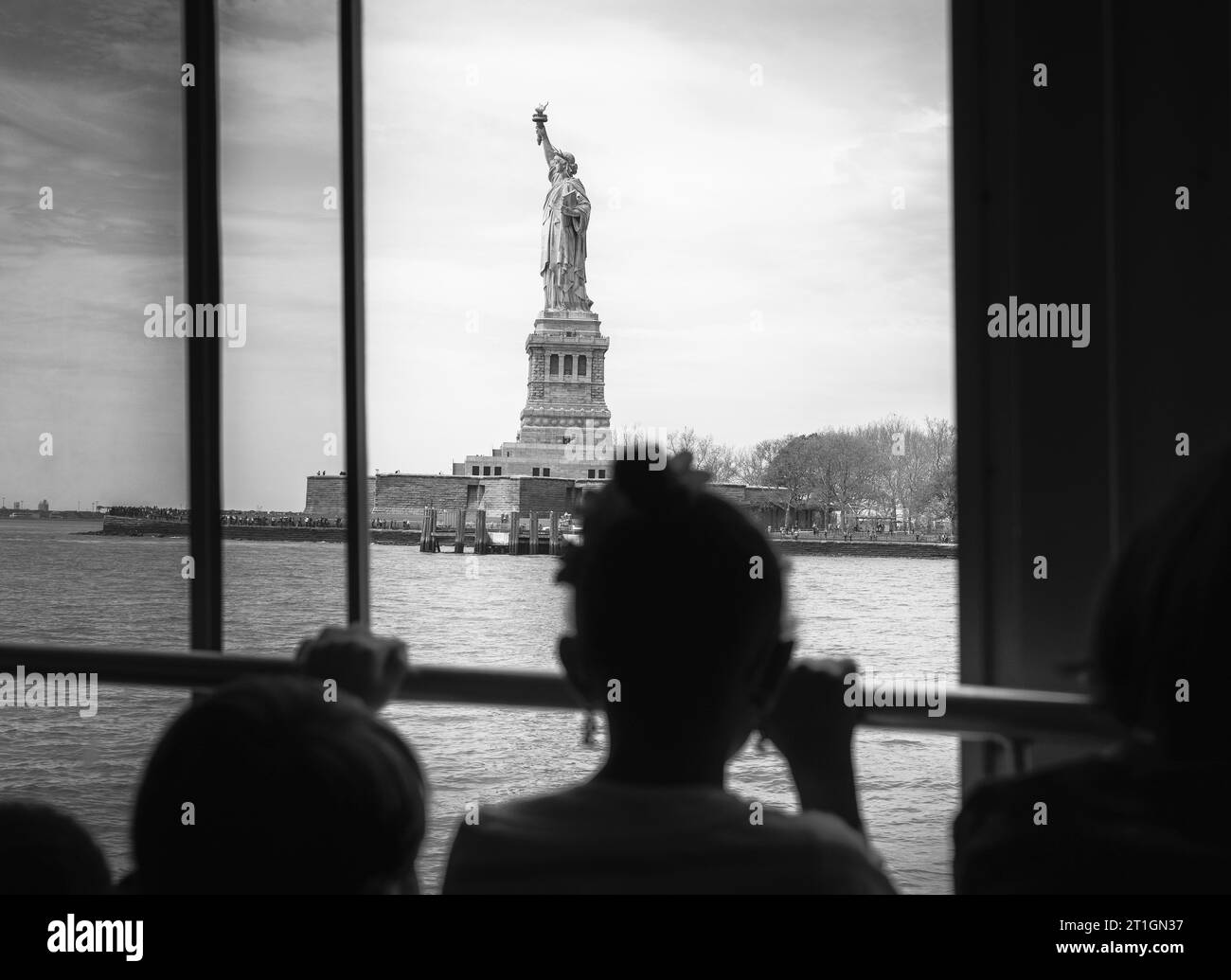 A young girl looks at the Statue of Liberty through a ferry window in New York City, USA. Stock Photo