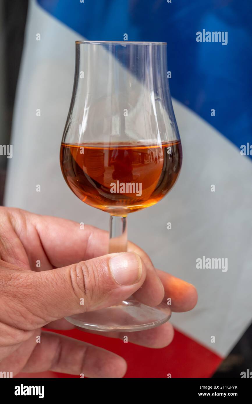 Tasting of aged cognac alcohol drink and view on French flag, town