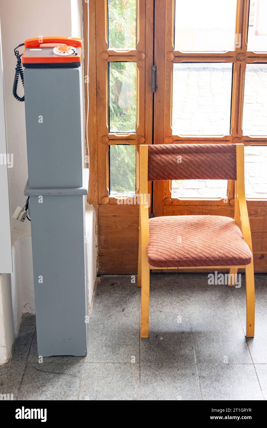 An empty chair with an old telephone at the entrance of the building Stock Photo
