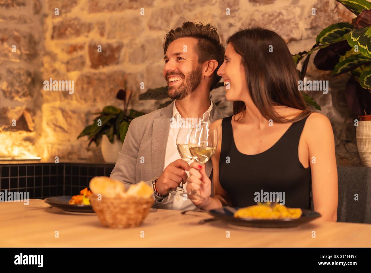 Lifestyle, a young European couple toasting drinks while having dinner in a restaurant, celebrating Valentine's Stock Photo