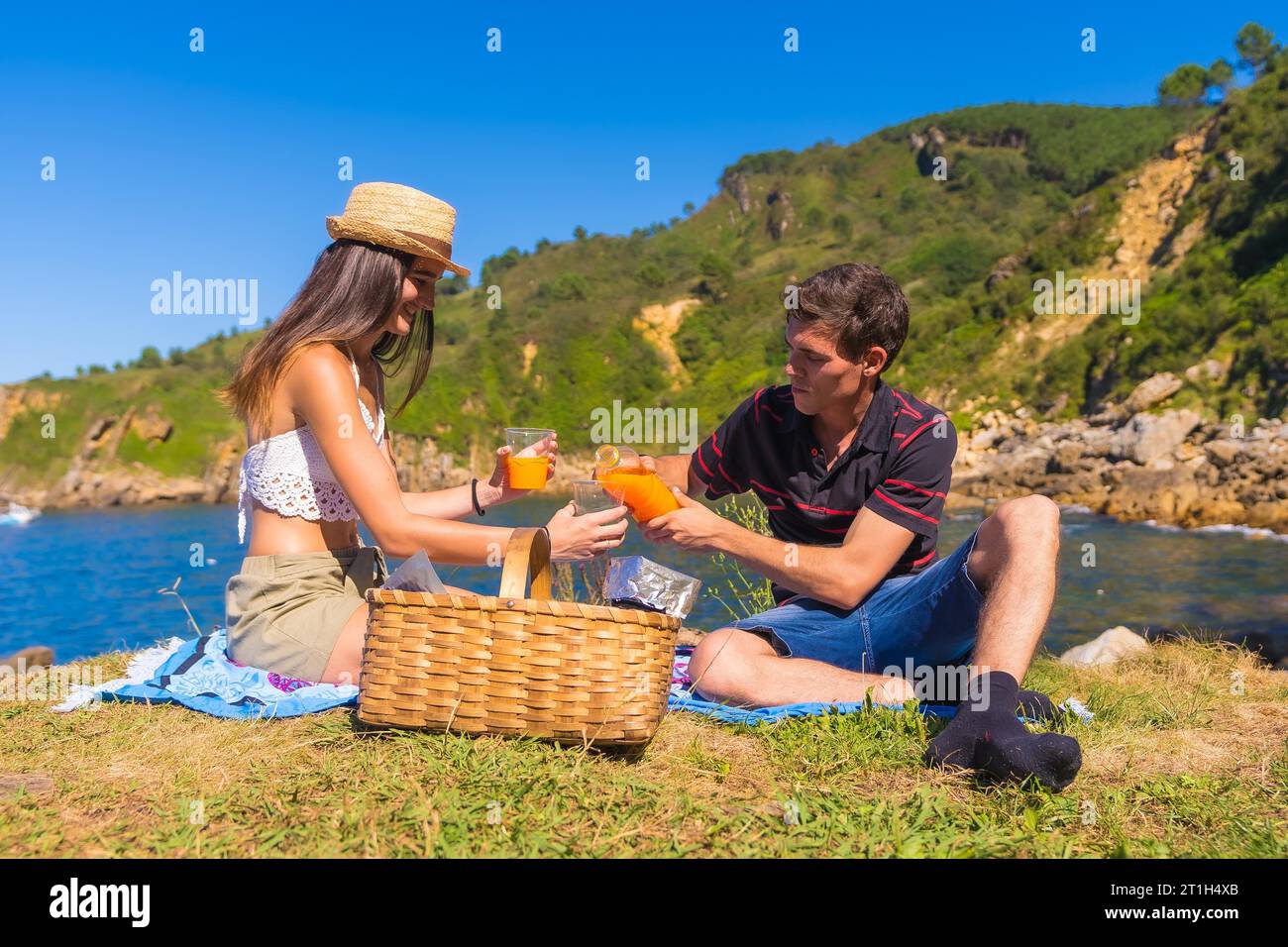 A young couple on a picnic in the mountains by the sea enjoying the summer Stock Photo