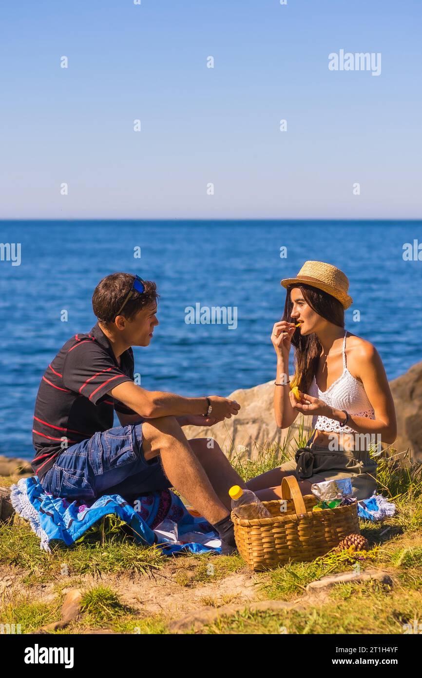 A couple eating potatoes at the picnic in the mountains by the sea enjoying the heat, summer lifestyle Stock Photo