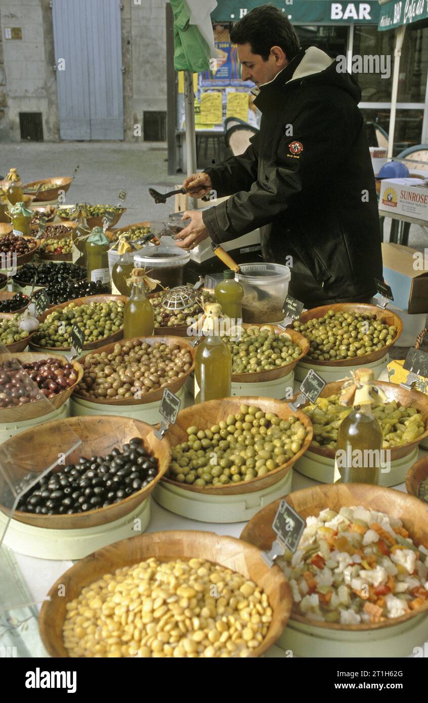Stallholder at the weekly market in provincial Pezenas, Herault, southern France, offers multiple varieties of processed olives Stock Photo