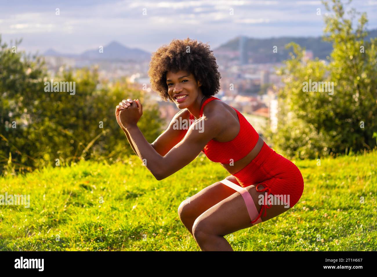 Fitness with a young black girl with afro hair, doing jumps and squats ...